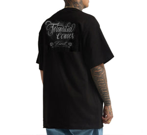 Person wearing a black t-shirt with text on the back, standing against a white background