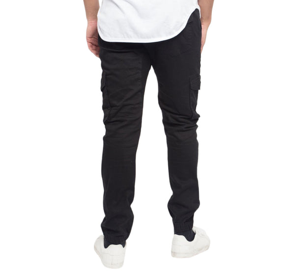 Person wearing black cargo pants and white shoes on a white background