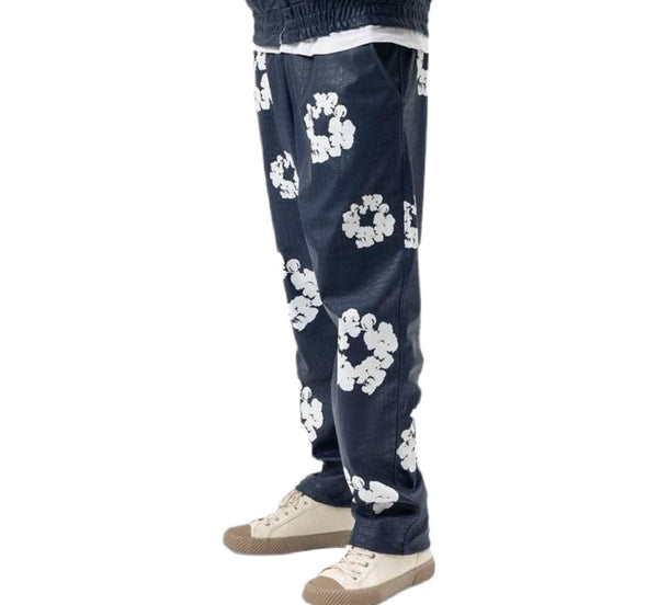 Navy blue pants with white floral patterns worn by a person on a white background