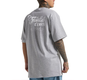 Person wearing a gray t-shirt with text on the back, standing against a white background