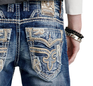 Close-up of blue jeans with intricate designs and branding on a white background